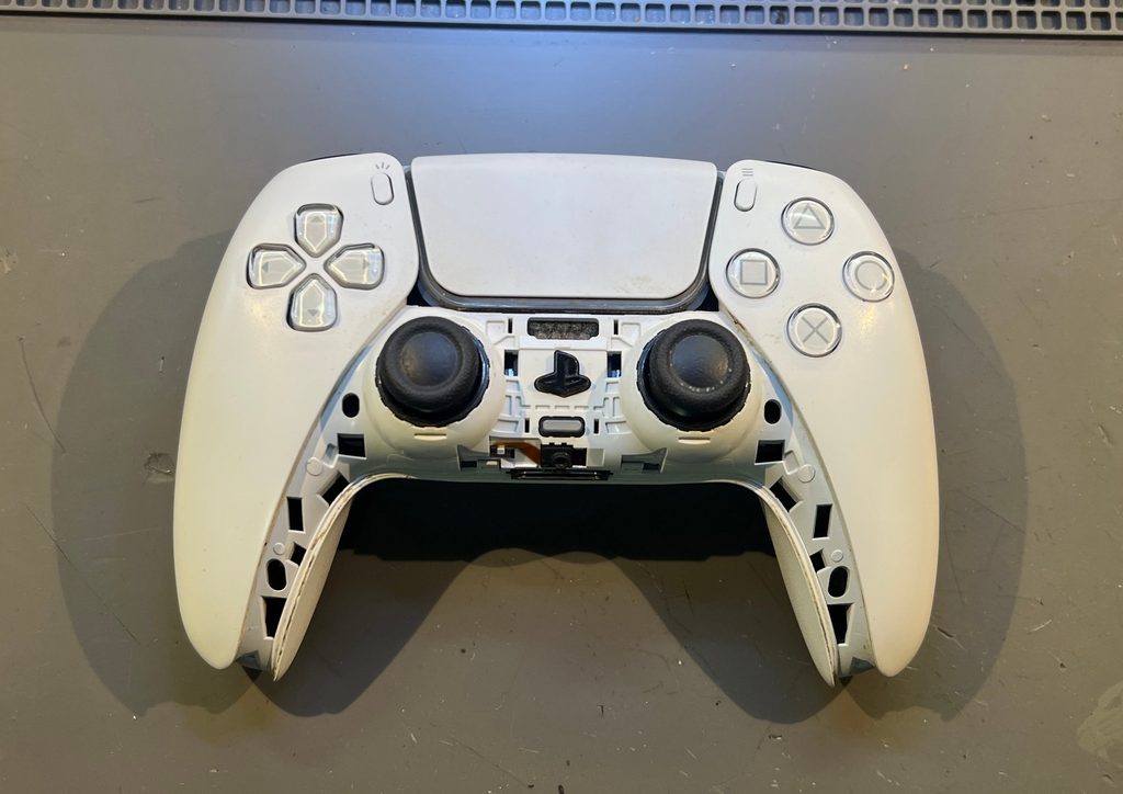 PS5 DualSense kontroler sa Stick Drift problemom na servisnom stolu, sa skinutim donjim delom kućišta